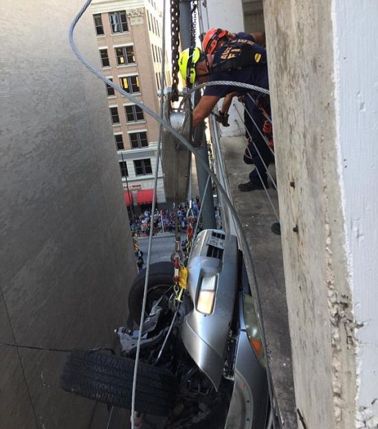 Свалившийся с 9 этажа парковки автомобиль зацепился за провода (6 фото